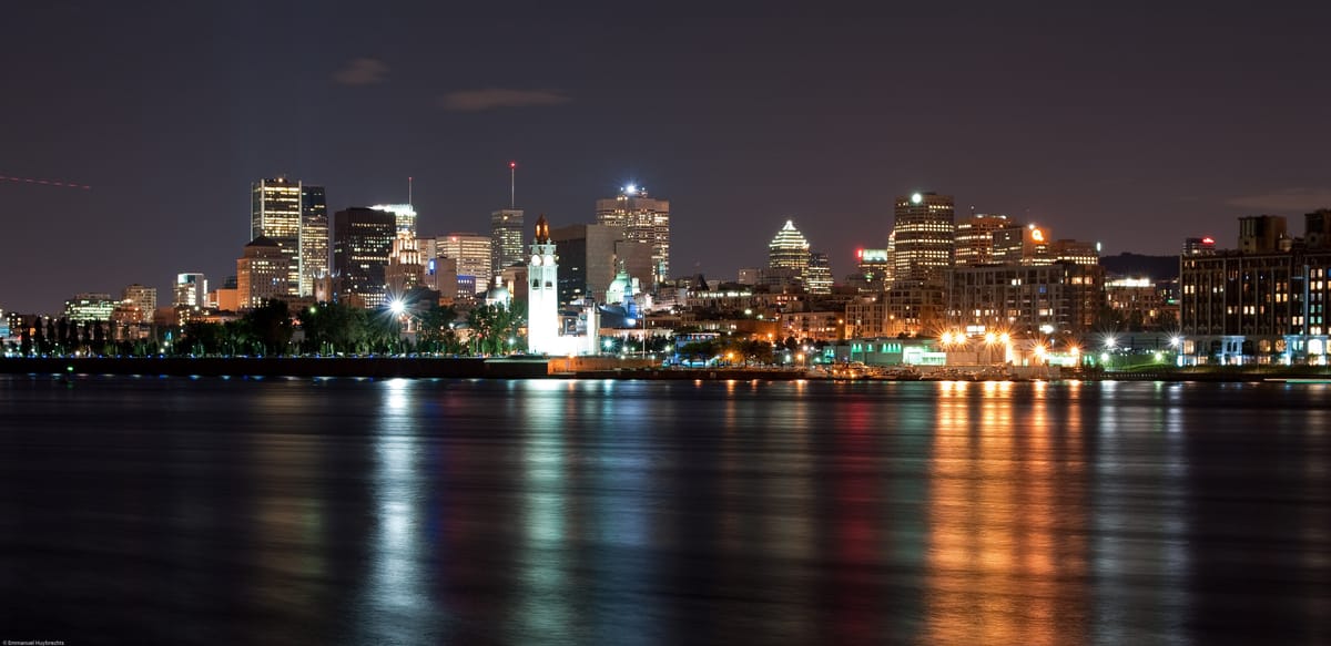 Le centre-ville de Montréal la nuit, reflété dans le fleuve